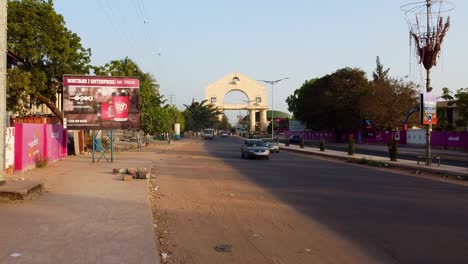Toma-Estática-Del-Tráfico-De-Gambia-Cerca-De-La-Entrada-Del-Arco-22-En-Banjul,-Al-Lado-De-La-Autopista.