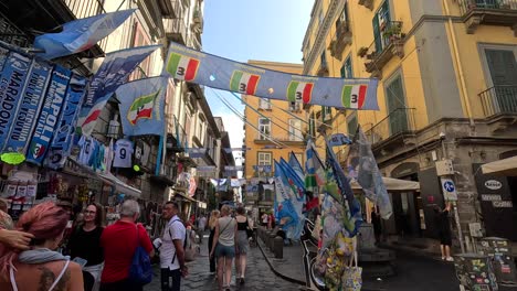 POV-Aufnahme-Eines-Spaziergangs-Durch-Eine-Schmale,-Farbenfrohe-Straße-Mit-Fußballsymbolen-Im-Stadtzentrum-Von-Neapel-In-Italien-Voller-Touristen