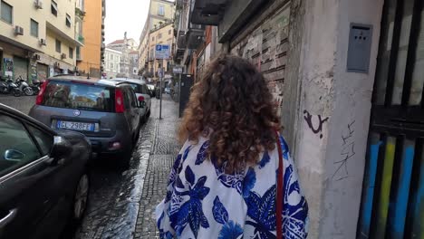 A-girl-is-walking-on-Naples-narrow-street-after-the-rain-near-the-parking