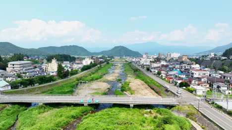 Aerial-tracking-shot-over-the-Yomase-river-and-the-Yudanaka-town,-summer-in-Japan