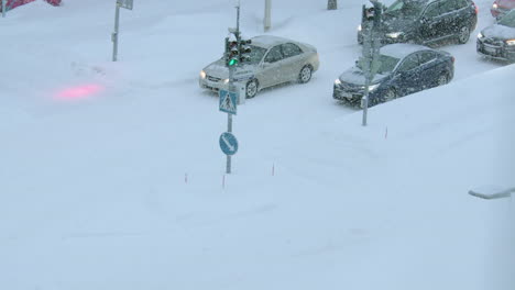 Der-Autoverkehr-Sitzt-An-Der-Straßenkreuzung-Im-Kalten-Winter-In-Der-Stadt,-Während-Schnee-Fällt