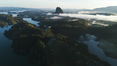 Cinematic-Aerial-Tilt-up-Reveal-of-Guatape,-Colombia-Landscape-at-Sunset