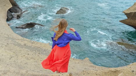 Woman-in-red-dress-admires-Atlantic-ocean-and-volcanic-coastline-of-Tenerife