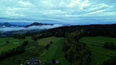 Aerial-drone-forward-moving-shot-over-green-farmlands-along-the-hilly-terrain-on-a-cloudy-day