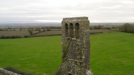 Fast-orbit-parallax-around-thin-brick-bell-tower-of-remnant-church-in-Irish-countryside