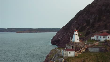 Rugged-cliffs-line-the-shore-and-bright-white-Fort-Amherst-lighthouse-at-edge-of-land