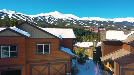 Panning-Drone-shot-of-Rustic-Mountain-Houses-in-Breckenridge,-Colorado,-Amazing-Snowy-Mountain-Vistas-in-Background