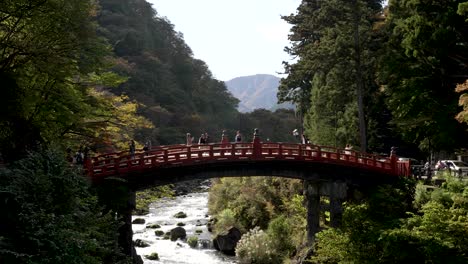 Shinkyo-Bridge-in-the-enchanting-surroundings-of-Nikko-with-slow-motion-capture,-individuals-gracefully-traversing-the-bridge