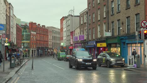 Roadside-shops-and-cars-in-a-city-center-in-Dublin,-Ireland