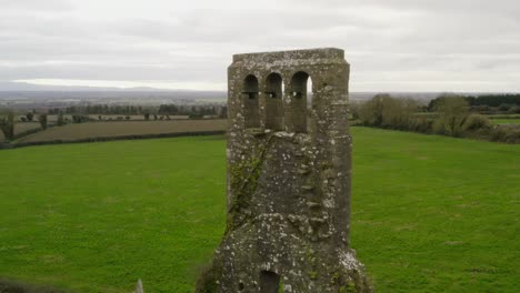 Aerial-orbit-around-brick-structure-remnants-of-bell-tower-at-church-in-green-countryside