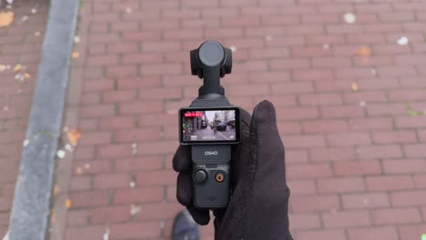 Gloved-hand-holding-Dji-Pocket-capturing-video-footage-in-the-city