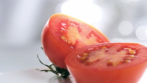Slow-motion-shot-of-Two-Tomato-Halves-rotating-against-white-blurred-background,-Close-up