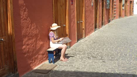 Beautiful-blonde-resting-on-bench-and-reading-in-city-of-Puerto-de-la-Cruz