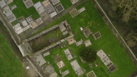 Drone-zenithal-top-down-view-rotates-above-cemetery-plots-and-old-church-walls