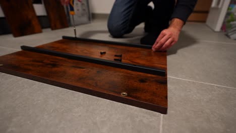 Closeup-of-man-assembling-wooden-table,-screwing-screws