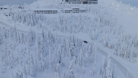 Luftaufnahme,-Die-Einem-Auto-Folgt,-Das-Auf-Den-Gipfel-Des-Iso-Syote-Fjälls-Fährt,-Winter-In-Finnland