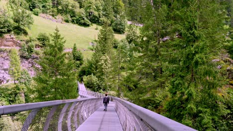Hiker-crossing-a-metal-bridge-over-the-Passer-river-on-the-Passer-Gorge-trail-in-the-Passeier-Valley-in-South-Tyrol,-Italy