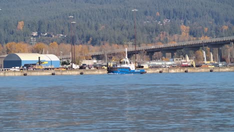 Tugboat-on-the-Fraser-River-with-Vancouver-cityscape-and-autumn-trees-in-the-background,-sunny-day