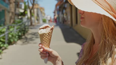 Happy-blonde-enjoys-delicious-ice-cream-in-Puerto-de-la-Cruz,-side-view