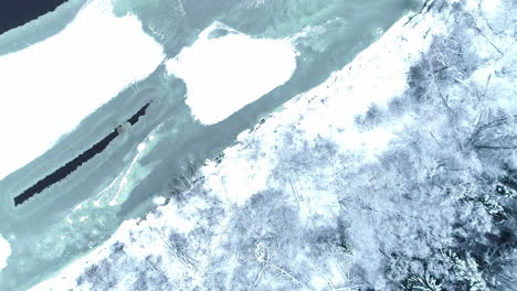 Aerial-top-down-view-of-winter-wonderland-with-frozen-lake-and-forest
