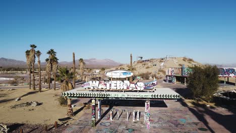 Aerial-footage-of-an-abandoned-waterpark-entrance-with-an-overview-of-the-land