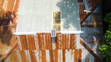 Panel-Solar-Recibiendo-Luz-Solar-En-El-Techo-De-Una-Casa-Rural-De-Estaño-En-Una-Zona-Remota-Del-Sur-De-Asia,-Bangladesh