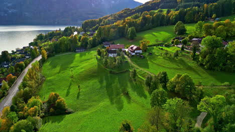 A-Rustic-Green-Landscape-Of-A-Village-Located-On-A-Hill-Near-A-Lake-With-Colourful-Trees