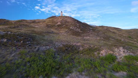 A-lighthouse-on-a-hill-in-los-roques-national-park-at-daytime,-clear-sky,-aerial-view