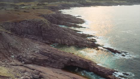 Strahlendes-Sonnenlicht-Spiegelt-Sich-Auf-Der-Meeresoberfläche-Wider-Und-Die-Wellen-Schlagen-Gegen-Eine-Zerklüftete-Küste-Im-Osten-Kanadas