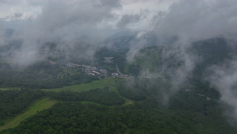 Flying-through-low-clouds,-toward-the-Shiga-Kogen-town,-summer-in-Japan---Aerial-view