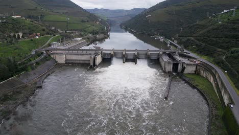 Regua-Dam-spillway-in-action-on-Douro-river,-Portugal---aerial