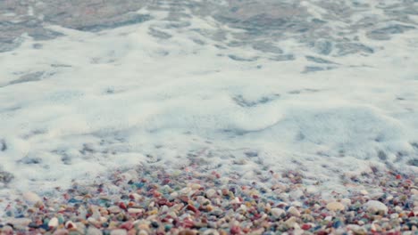 Stunning-4k-video-of-a-rocky-beach-with-foamy-blue-waves-and-multiple-colour-stones