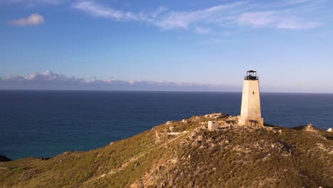 Old-lighthouse-on-a-rugged-coastline-overlooking-the-sea,-clear-sky