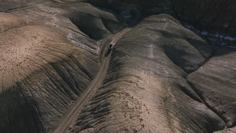 Geländewagen-Fährt-Durch-Enge-Schluchten-Zwischen-Runden-Und-Faltigen-Hügeln-Der-Mondlandschaft,-Factory-Butte-In-Utah,-USA