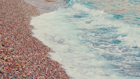 Stunning-4k-video-of-a-rocky-beach-with-foamy-blue-waves-and-multiple-colour-stones