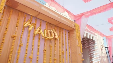 Handheld-low-angle-shot-of-wall-decorated-with-balloons-writing-HALDI,-Indian-Wedding