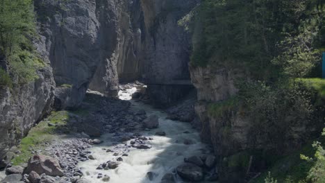 Sich-Bewegende-Stromschnellen-An-Der-Öffnung-Einer-Bergschlucht-Mit-Windwehenden-Bäumen-|-Grindelwald-Schweiz-Höhle-Im-Gletschercanyon,-Europa,-4k