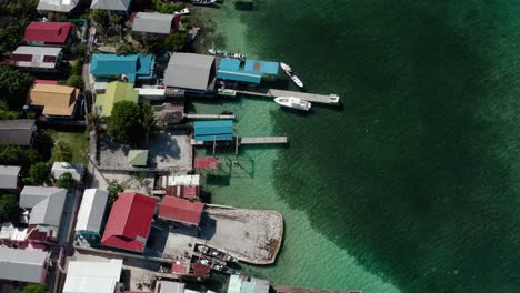 Aerial-Drone-Fly-Above-Sea-Coastline,-Colorful-Houses-of-Utila-Bay-Islands,-Honduras,-in-the-Caribbean