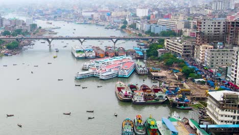 Vista-Aérea-De-Los-Barcos-Atracados-A-Lo-Largo-De-La-Orilla-Del-Río-Buriganga-En-El-Puerto-Más-Activo-De-Dhaka,-Bangladesh