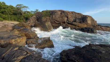 A-pristine-island-on-a-sunny-day,-with-water-crashing-against-the-rocks