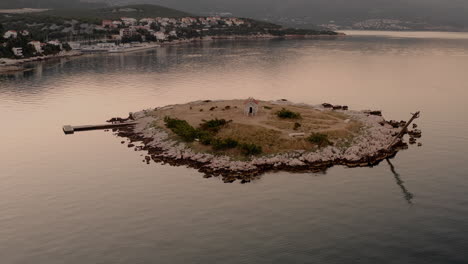 Small-island-near-the-coastline-in-the-middle-of-the-sea,-church-on-a-deserted-island,-quiet-water,-calm-Adriatic-sea,-early-morning,-sunrise,-golden-hour,-Croatia,-Novi-Vinodolski,-summer-holiday