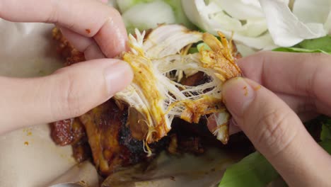 Closeup-of-hands-peeling-ayam-bakar-indonesian-grilled-chicken-with-cabbage