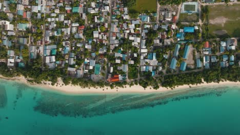 An-Aerial-Shot-Of-A-Tropical-Coastal-Village-With-A-Tree-Line-Along-The-Beach