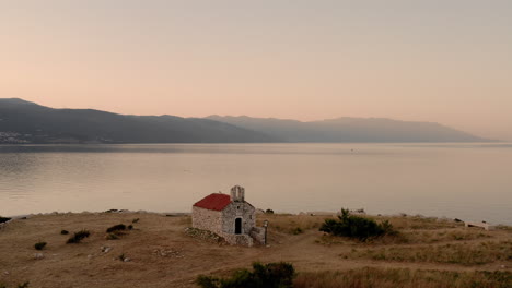 Panoramic-view-of-the-Sveti-Marin-Chapel-during-sunrise,-Novi-Vinodolski,-Croatia,-cinematic-aerial-shot-of-a-church-on-an-island-with-seagulls-flying-by,-golden-hour-view-of-the-peaceful-Adriatic-sea