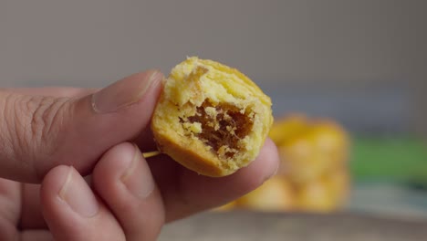 Hand-holds-nastar-with-bite-taken-out-of-yumy-Indonesian-pineapple-filled-cookie