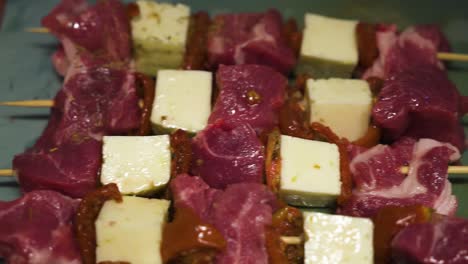 Beef-skewers-with-tofu-being-seasoned,-close-up-view