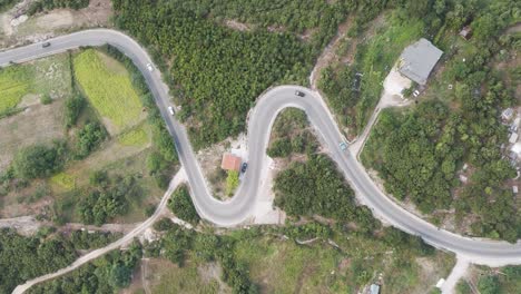 Aerial-descend-over-cars-drive-on-serpentine-mountain-road-in-Albania