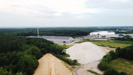 New-modern-factories-and-sand-piles-for-construction,-aerial-view