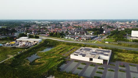 Industrial-side-of-Aalst-city-with-downtown-in-horizon,-aerial-view