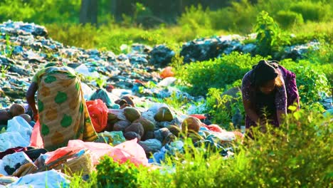 Two-woman-worker-sorting-trash-on-a-dirty-landfill,-third-world-poor-labor